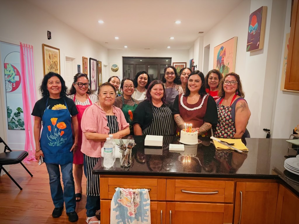 Hay Comida en la Casa participants gathered together in aprons after class