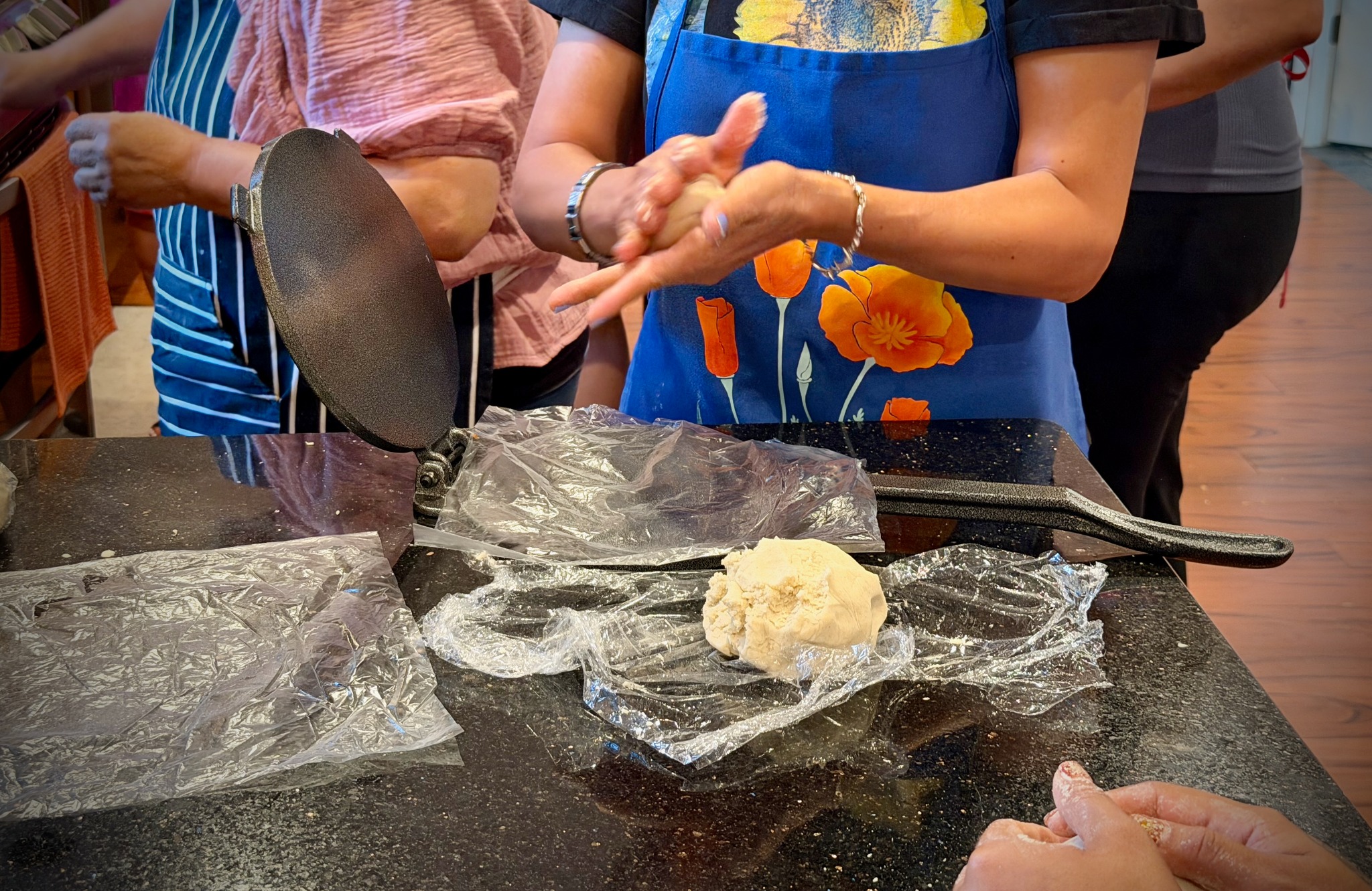 Class participant shaping masa beside an open tortilla press
